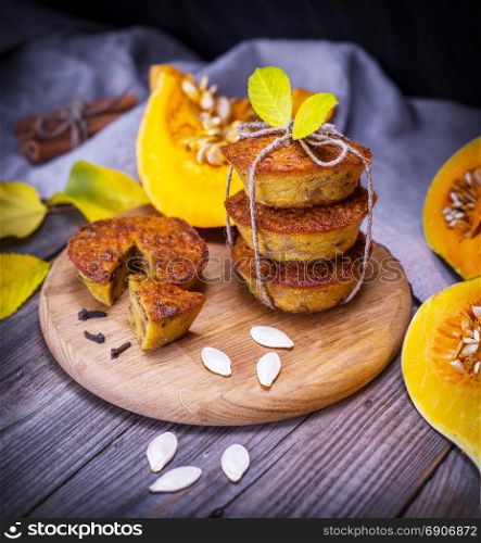sweet pumpkin muffins on a wooden plank with fresh pieces of pumpkin