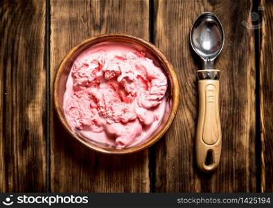 Sweet raspberry ice cream with a spoon. On a wooden table.. Sweet raspberry ice cream with a spoon.