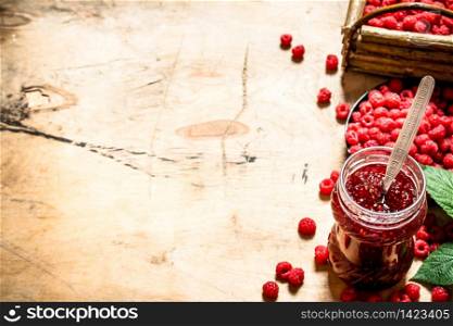 Sweet raspberry jam in jar with spoon. On a wooden table.. Sweet raspberry jam in jar with spoon.