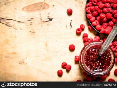 Sweet raspberry jam in jar with spoon. On a wooden table.. Sweet raspberry jam in jar with spoon.