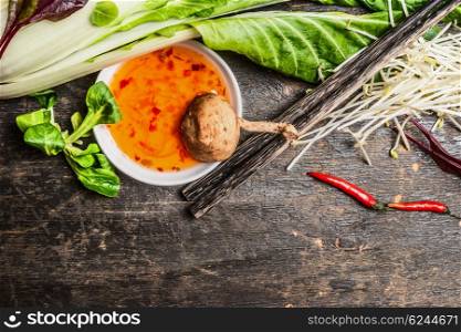 Sweet-sour sauce with Shiitake mushrooms, pak choi and chopsticks on rustic background, top view. Asian cooking ingredients. Asian food concept.