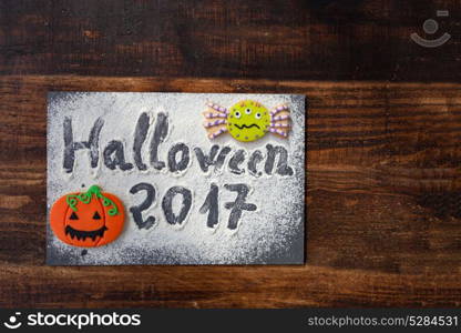 "Sweet terror is coming. The words "Halloween 2017" on a slate with flour and cookies"