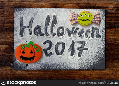 "Sweet terror is coming. The words "Halloween 2017" on a slate with flour and cookies"