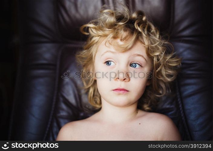 Sweet thoughtful little girl sits in armchair