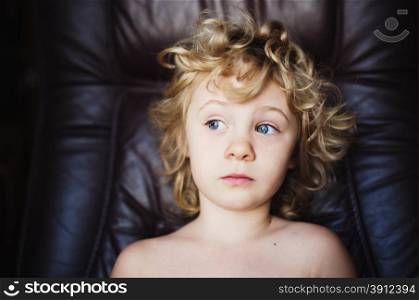 Sweet thoughtful little girl sits in armchair