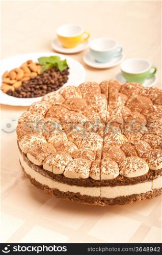 sweet tiramisu cake with almonds, coffee beans and cups