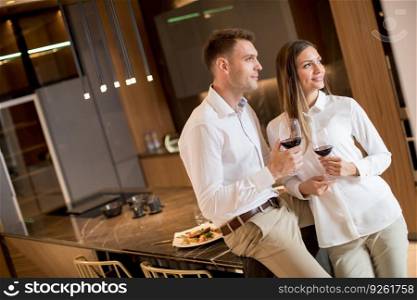 Sweet young couple drinking red wine after romantic dinner at luxury kitchen