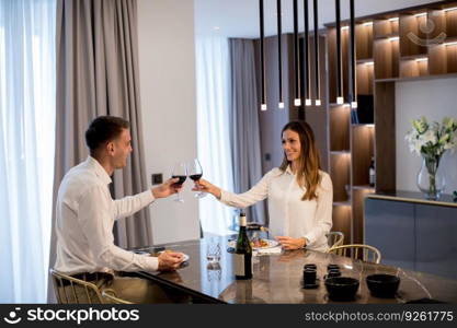 Sweet young couple having a romantic dinner and toasting with glasses of red wine at luxury kitchen