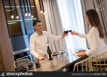 Sweet young couple having a romantic dinner and toasting with glasses of red wine at luxury kitchen