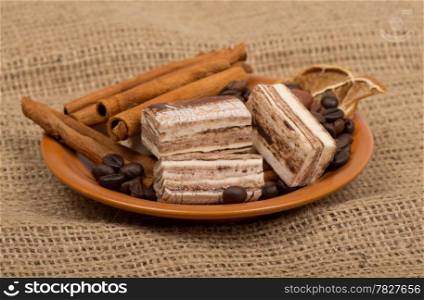Sweets, cinnamon, nuts and coffee beans on a saucer.
