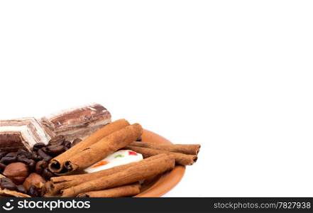 Sweets, cinnamon, nuts and coffee beans on a saucer isolated on white