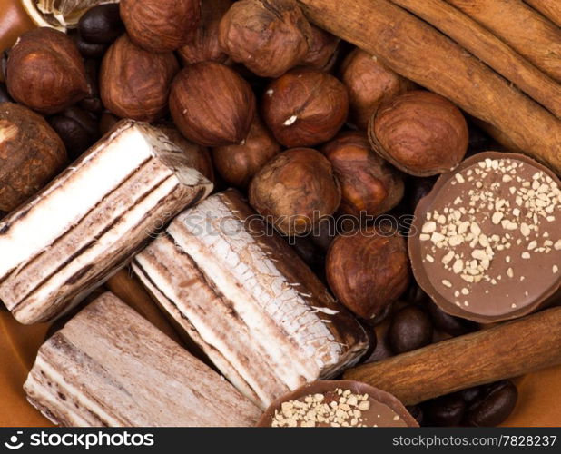 Sweets, cinnamon, nuts and coffee beans on a saucer, on burlap background.