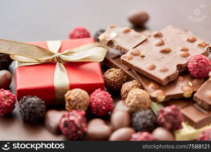 sweets, confectionery and food concept - close up of different chocolate bars, candies and gift box on brown background. close up of different chocolates, candies and gift