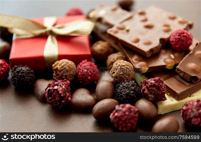 sweets, confectionery and food concept - close up of different chocolate bars, candies and gift box on brown background. close up of different chocolates, candies and gift