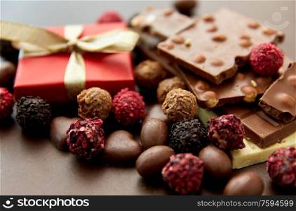sweets, confectionery and food concept - close up of different chocolate bars, candies and gift box on brown background. close up of different chocolates, candies and gift