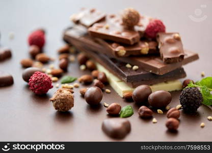 sweets, confectionery and food concept - close up of different chocolate bars, candies and nuts on brown background. close up of different chocolates, candies and nuts