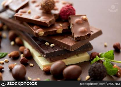 sweets, confectionery and food concept - close up of different chocolate bars, candies and nuts on brown background. close up of different chocolates, candies and nuts