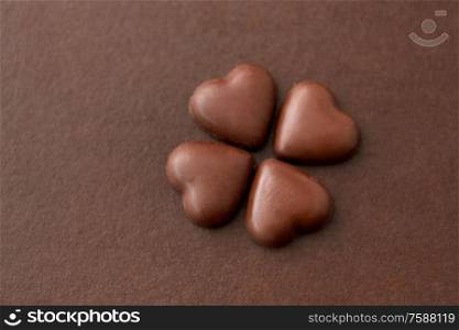 sweets, confectionery and food concept - heart shaped chocolate candies on brown background. heart shaped chocolate candies