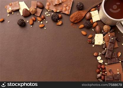 sweets, confectionery and food concept - hot chocolate with nuts, candies and cocoa powder on brown background. hot chocolate with nuts, cocoa powder and candies