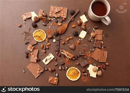 sweets, confectionery and food concept - hot chocolate with nuts, candies, cinnamon and cocoa powder on brown background. hot chocolate with nuts, cocoa powder and candies