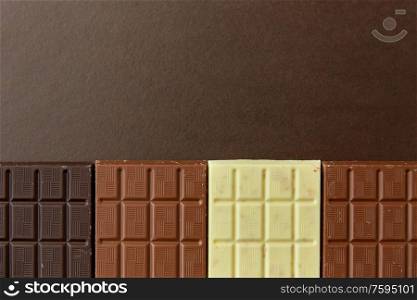 sweets, confectionery and food concept - milk, dark and white chocolate bars on brown background. different kinds of chocolate on brown background