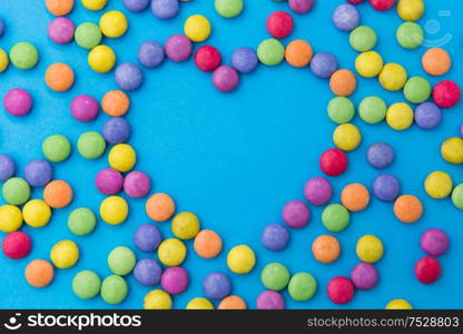 sweets, confectionery and valentine&rsquo;s day concept - bright multicolored candy drops in shape of heart on blue background. candy drops in shape of heart on blue background