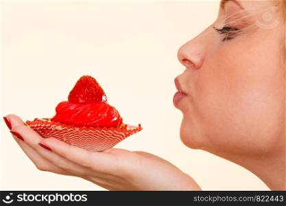 Sweets, junk food, sugar temptation on diet concept. Woman holding sweet delicious cupcake sending air kisses to dessert.. Woman holding sweet delicious cupcake
