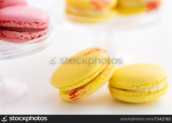 sweets, pastry and food concept - close up of lemon yellow and pink macarons over white background. close up of yellow and pink macarons