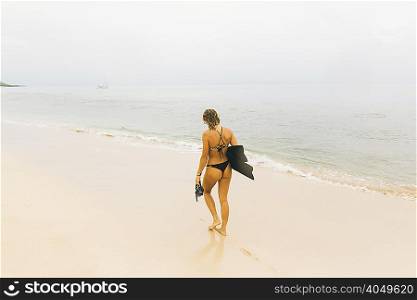 Swimmer carrying flippers, walking on beach
