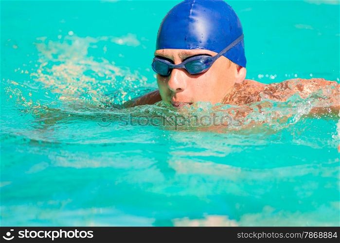 swimmer in blue cap and goggles swimming in the pool