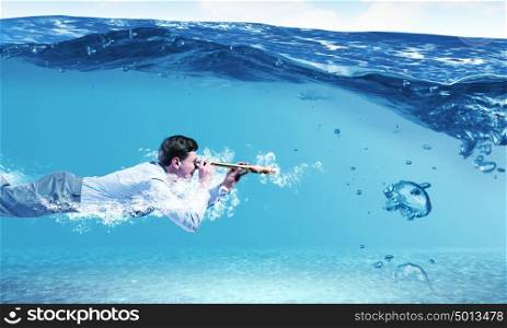 Swimming businessman. Young businessman in suit swimming under water