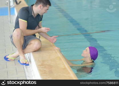 swimming coach holding stopwatch poolside at the leisure center