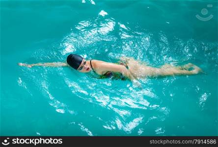 Swimming. Competition and recreation. Woman swimmer breathing performing crawl style. Poolside.