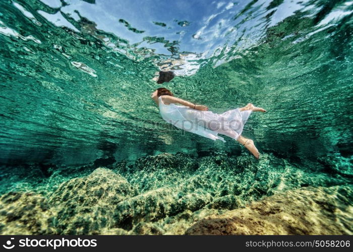 Swimming in transparent sea, emerges from clear sea, wearing fashionable white dress, luxury summer vacation, freedom and enjoyment concept