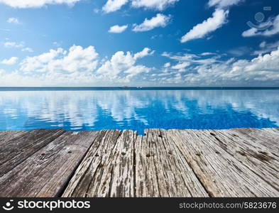 Swimming pool and old wooden pier in the tropical hotel