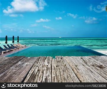Swimming pool and old wooden pier in the tropical hotel