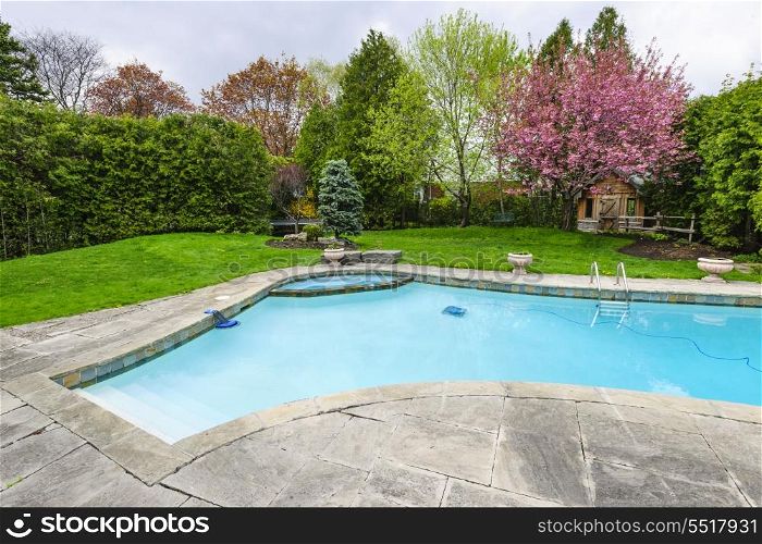 Swimming pool in backyard. Backyard with outdoor inground residential private swimming pool and stone patio