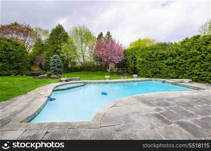 Swimming pool in backyard. Backyard with outdoor inground residential private swimming pool and stone patio