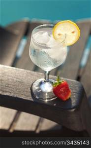 Swimming pool, lounge, a wine glass with ice, lemon and strawberry
