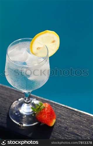 Swimming pool, lounge, a wine glass with ice, lemon and strawberry