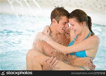 Swimming pool - young loving couple have fun under water stream