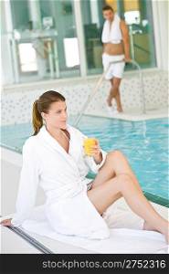Swimming pool - young woman relax on poolside, hold orange juice