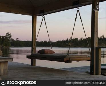 Swing chair on a dock at sunset, Lake of The Woods, Ontario, Canada