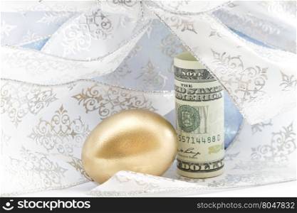 Swirls of silver and light blue ribbon surround gold egg and American dollar. Generous gifting adds to successful savings. Retirement joy shows in successful investment planning.