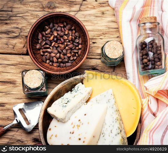 Swiss cheese with cedar nut. Three varieties of cheese with pine nuts on a retro wooden background