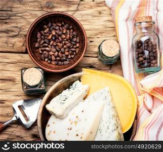 Swiss cheese with cedar nut. Three varieties of cheese with pine nuts on a retro wooden background