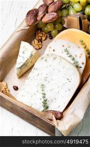 Swiss cheese with nuts. Cheese with coriander and nettle, dates and grapes on a retro wooden background