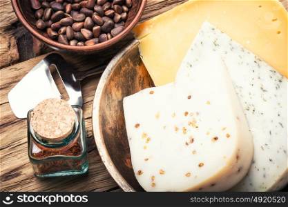 Swiss cheese with pine nuts. Three varieties of cheese with pine nuts on a retro wooden background