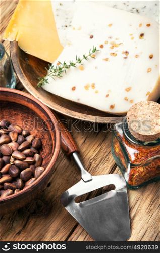 Swiss cheese with pine nuts. Three varieties of cheese with pine nuts on a retro wooden background