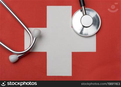 Swiss flag and stethoscope. The concept of medicine. Stethoscope on the flag in the background.. Swiss flag and stethoscope. The concept of medicine.